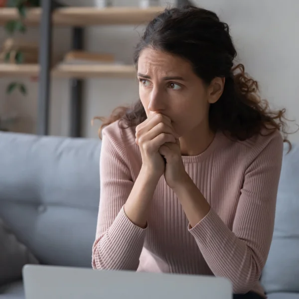 Woman rests her chin on her hands while seated on a couch, reflecting on the challenges of securing bad credit loans.